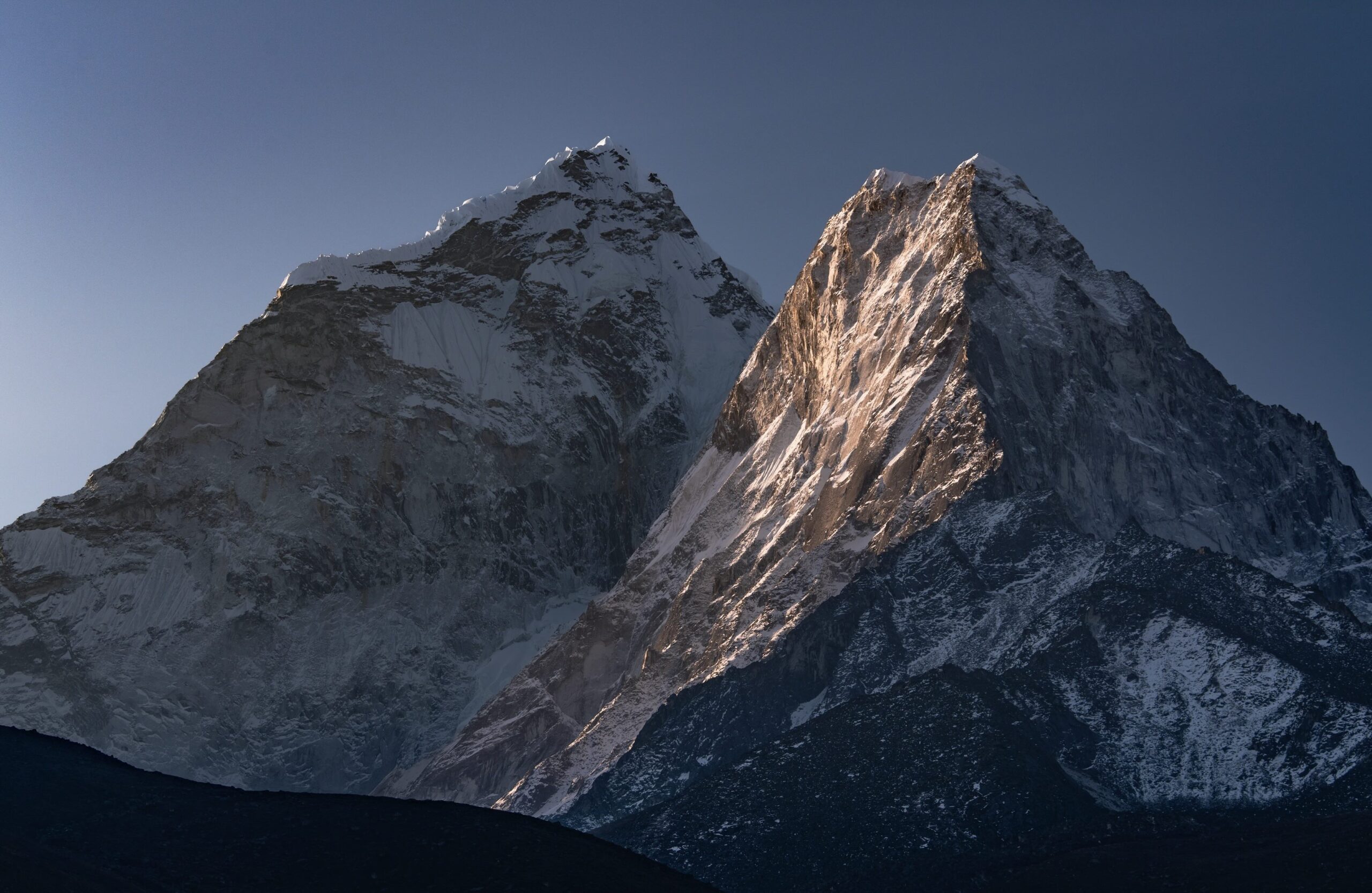 A photograph looking up at the twin peaks of Nepal's mountain, Ama Dablam at sunrise.