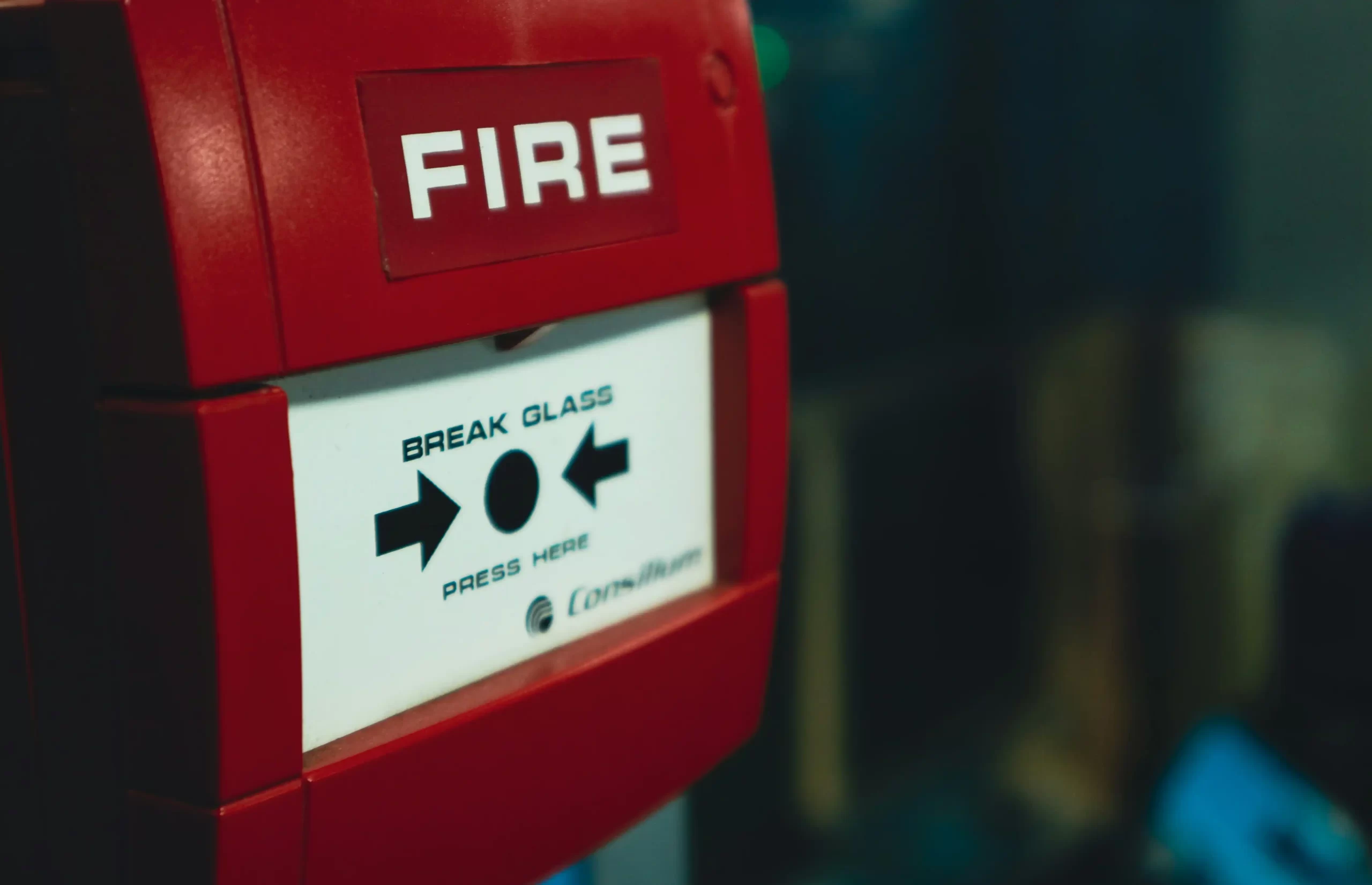 A wall-mounted glass-break style fire alarm trigger.